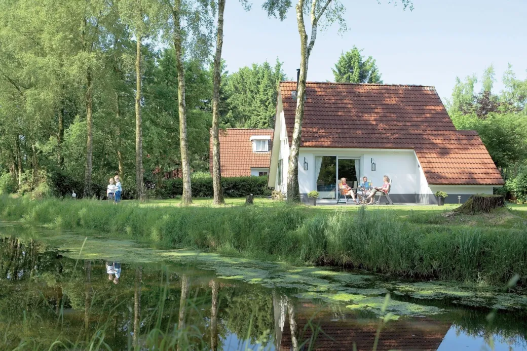 Mensen zitten op het terras bij hun bungalow aan het water