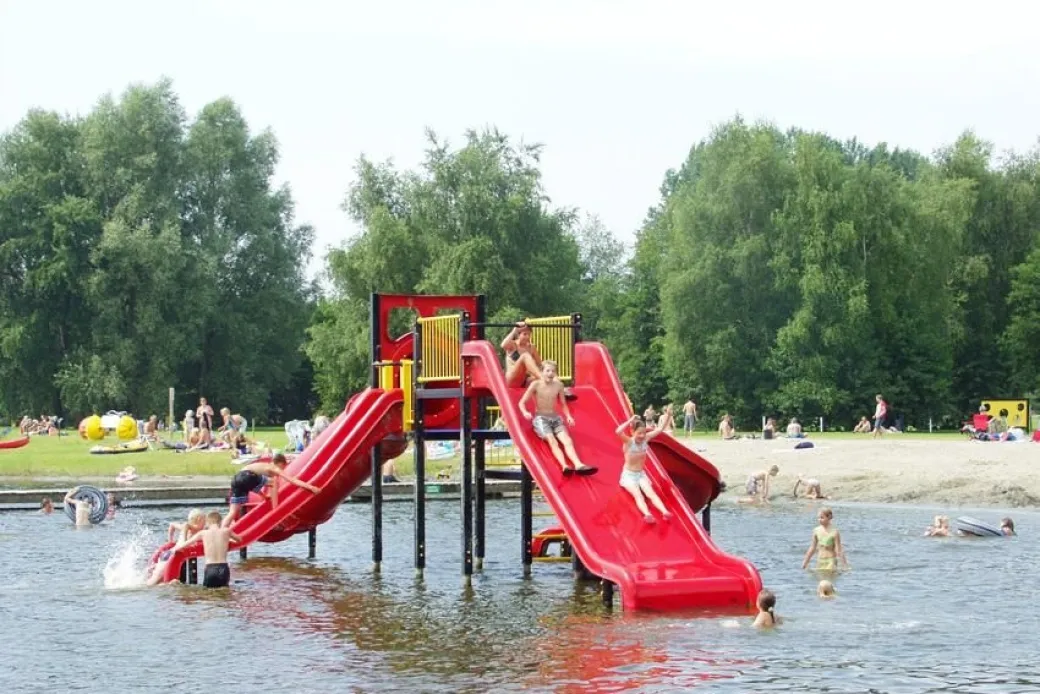 Kinderen glijden van de glijbaan in het waterplas