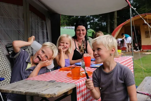 Kinderen zitten buiten bij hun eigen caravan