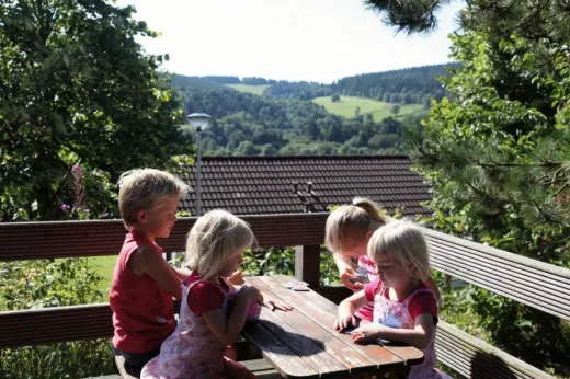 KInderen zitten op het terras bij 1 van de bungalows