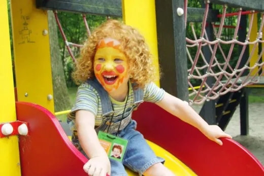 Meisje gaat van de glijbaan in de speeltuin