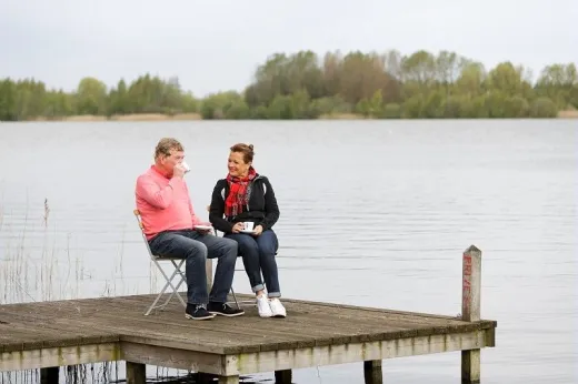 Stel zit op houten flonder aan het water